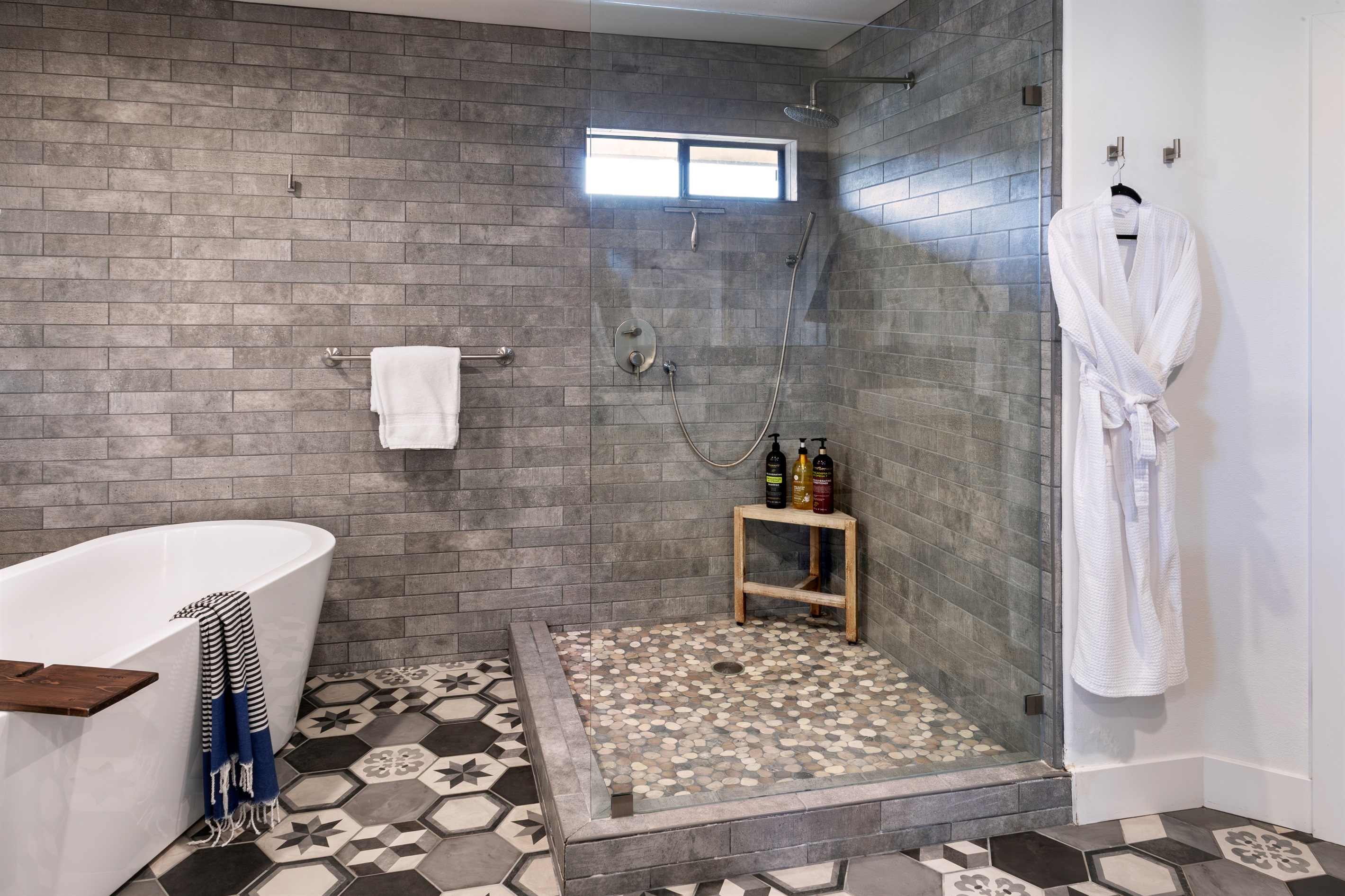 Your private spa awaits. An oversized walk-in rainfall shower, artisan pebble tile, and a freestanding soaking tub — all dressed in beautiful encaustic hex tile flooring.