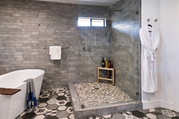 Your private spa awaits. An oversized walk-in rainfall shower, artisan pebble tile, and a freestanding soaking tub — all dressed in beautiful encaustic hex tile flooring.