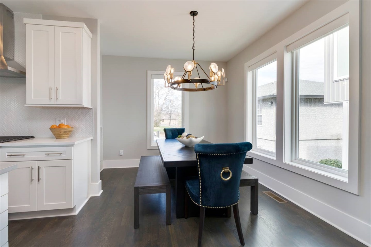 - Velvet blue chairs, wood bench seating, and a bold circular chandelier set the scene - Surrounded by tall windows with plenty of daylight for morning meals or evening dinners - Stylish and cozy spot to gather over coffee, dinner, or board games