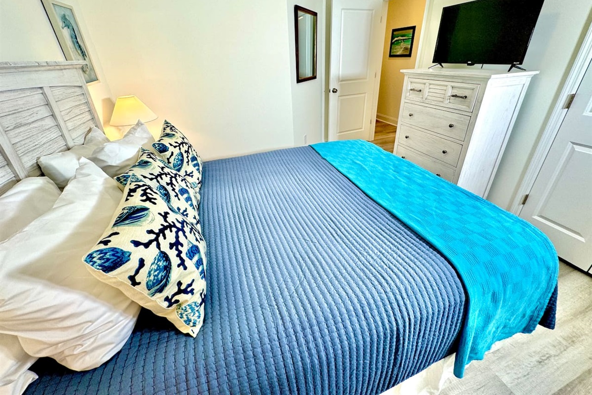 Queen bed with a smart TV and blackout curtains.