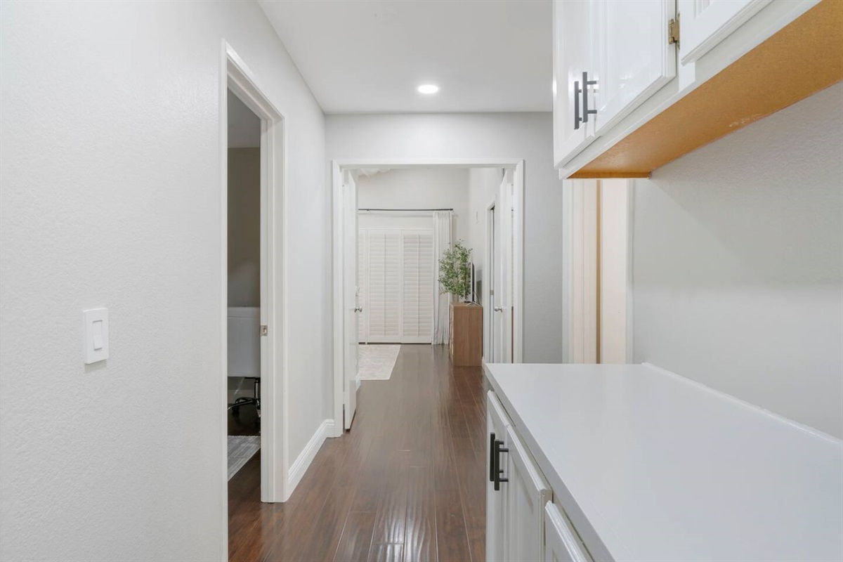 The hallway between the bedrooms and the second bathroom features ample cabinets for storage. The clean, functional space provides easy access to the iron and ironing board, while keeping the area tidy and organized.