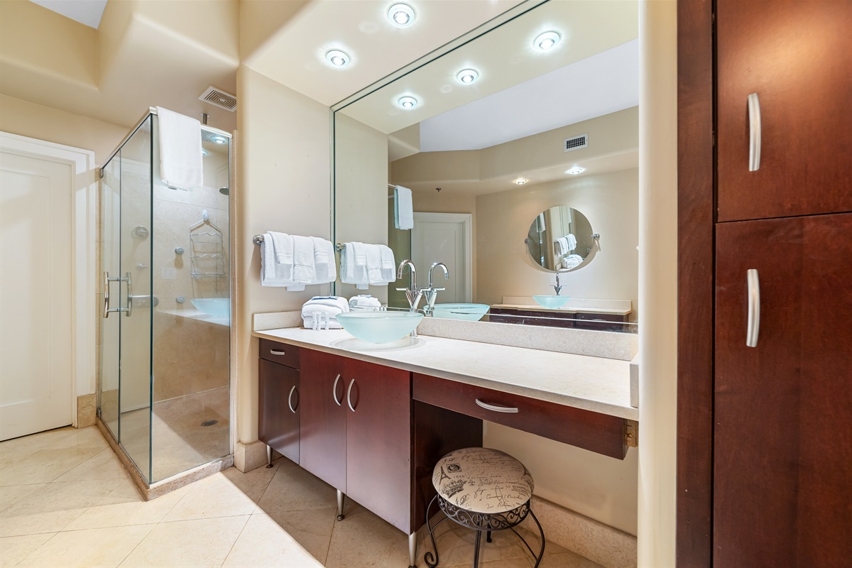 Modern bathroom showcasing a glass shower, spa-like soaking tub, vessel sink, and ample counter space, designed for both beauty and practicality.