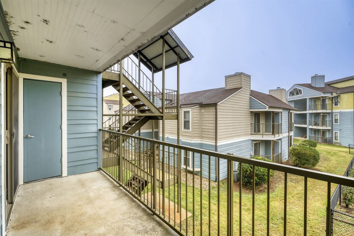 Quiet balcony space with a clear view of the courtyard and nearby buildings.