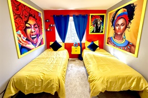 A bright and colorful twin bedroom adorned with vibrant artwork and yellow bedding, ideal for relaxation.