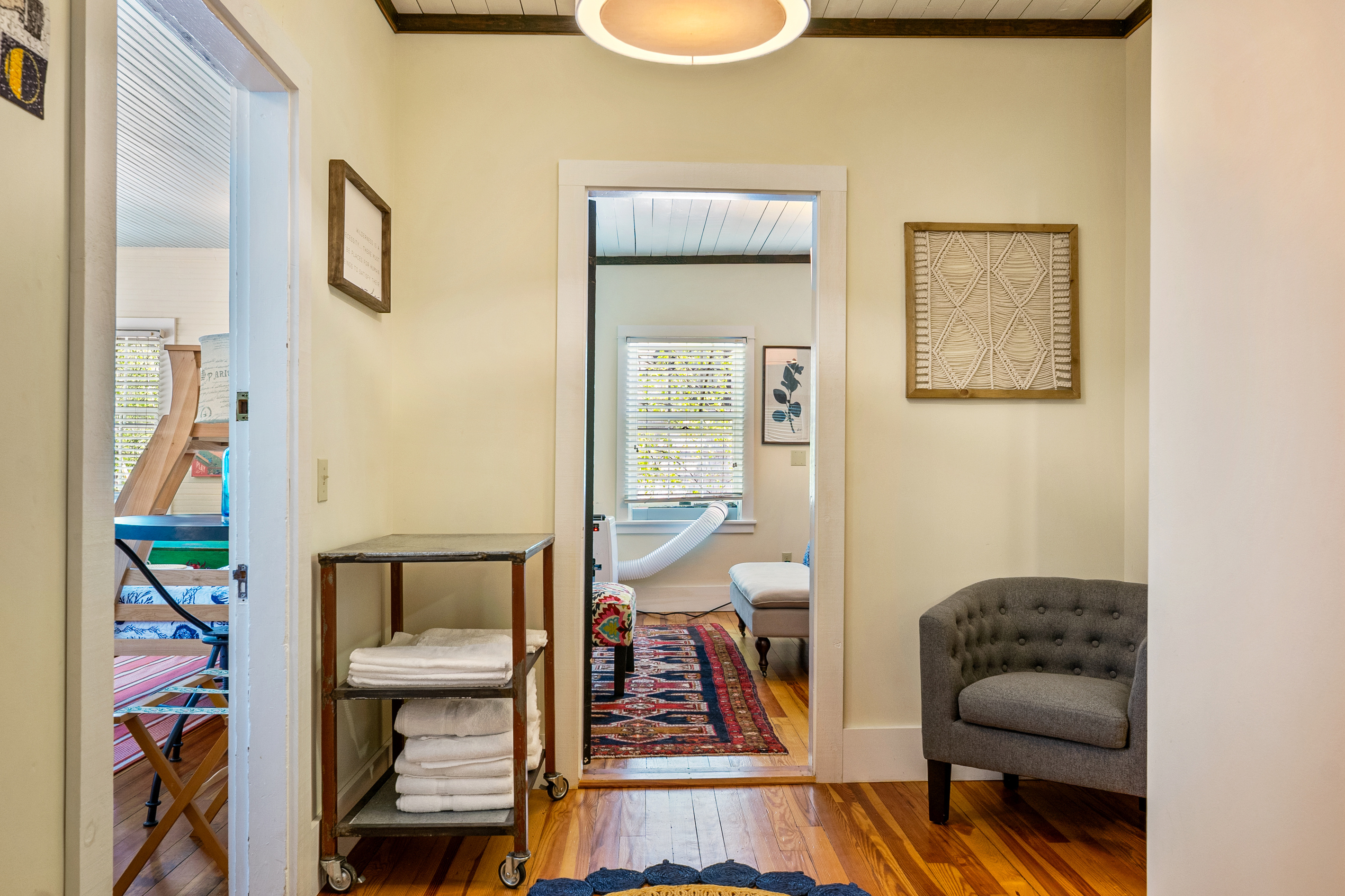 The central junction of the crew's wing connects the bunk room and the second King bedroom. A vintage rolling metal cart stands ready, stocked with fresh towels to handle the daily logistics of a busy, active crew returning from the shore.