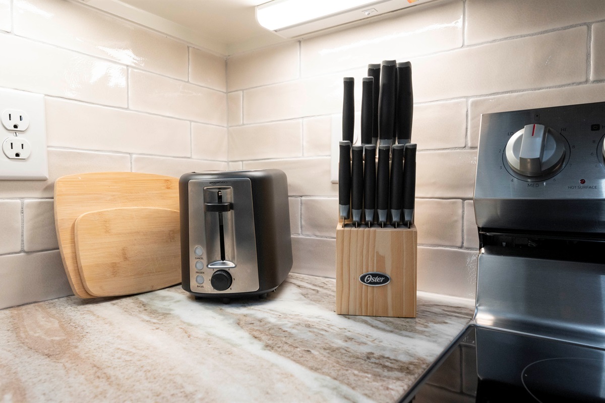 Essential kitchen tools, including sharp knives, a toaster, and cutting boards, are ready for meal prep convenience.