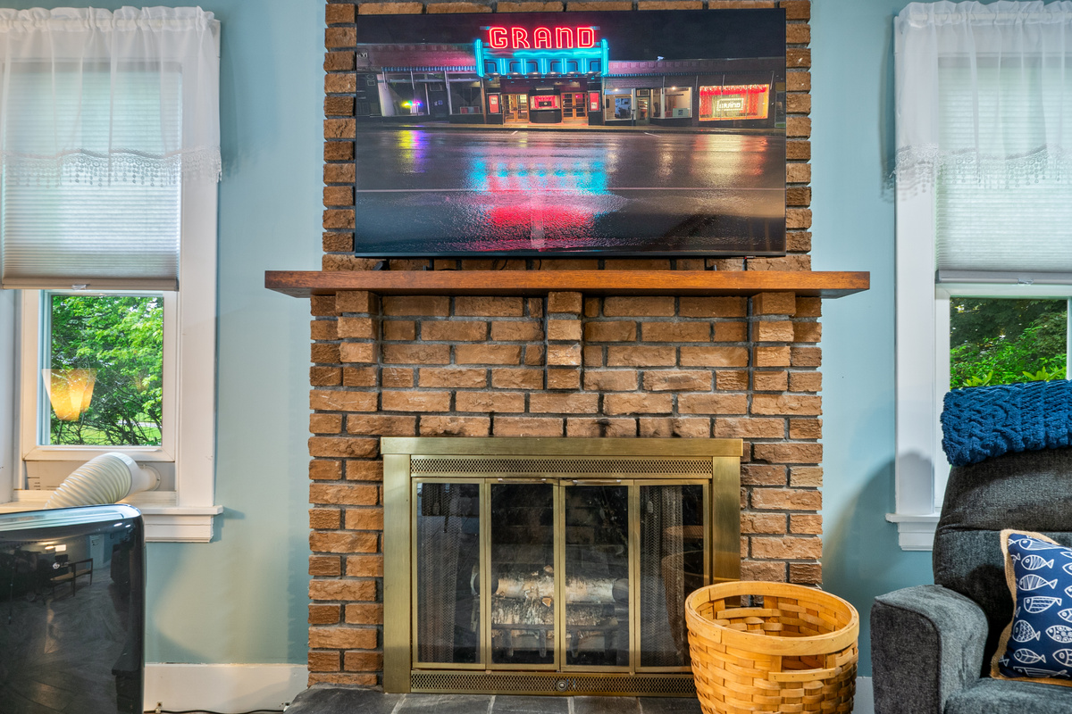 Gather around the fireplace for a family movie night. This central media hub features a wide flat-screen TV mounted securely over a classic brick hearth, making it the perfect spot for your group to stream favorite shows and relax after a day of exploring.