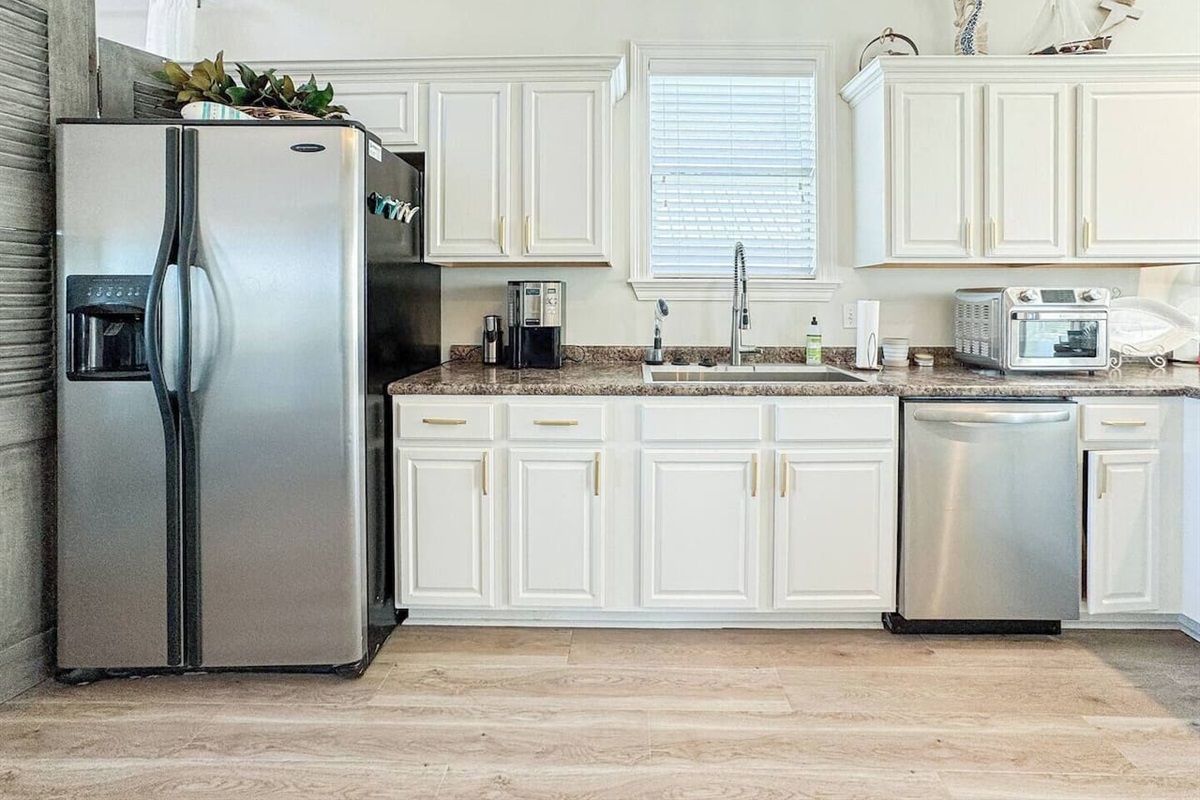 Spacious, sunlit kitchen featuring ample counter space, stainless steel appliances, and stylish lighting, perfect for cooking.