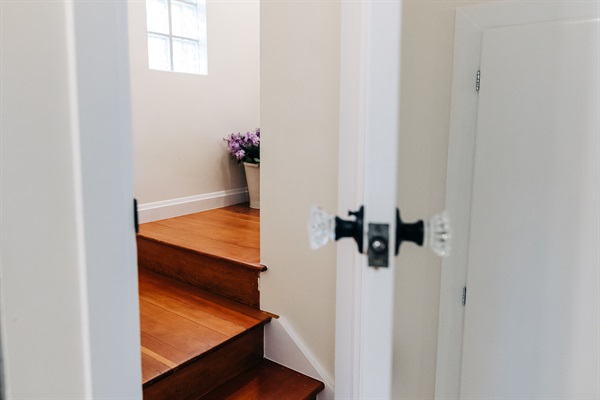 Glass door knobs, flooded with natural light and squeaky as old stairs should be. Its easy to miss the stairs to the second floor. It blends in to all the other kitchen buil-in cabinetry.