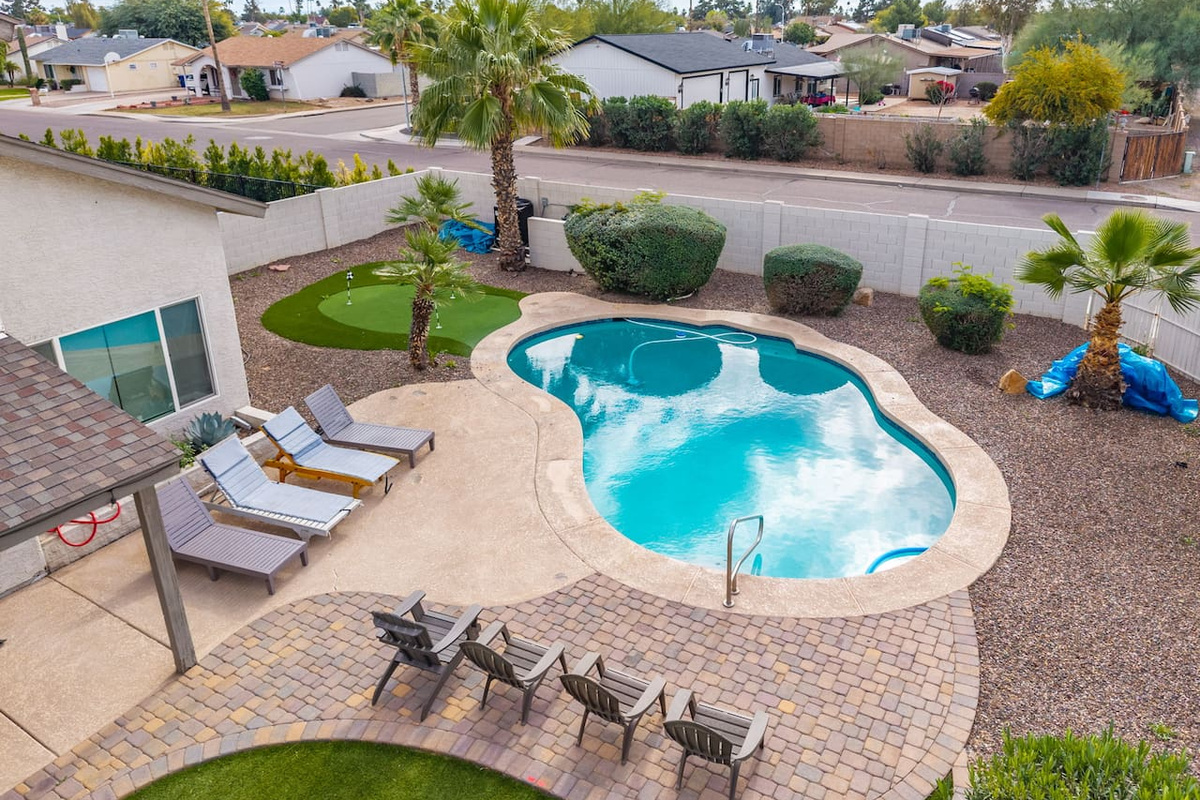 Resort-style backyard with sparkling pool, spa, putting green, and multiple lounging areas.