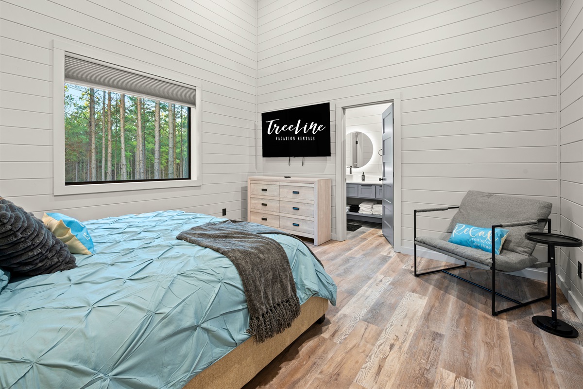 Natural light fills the room through large windows, bringing in views of the surrounding forest while keeping the space bright and welcoming.