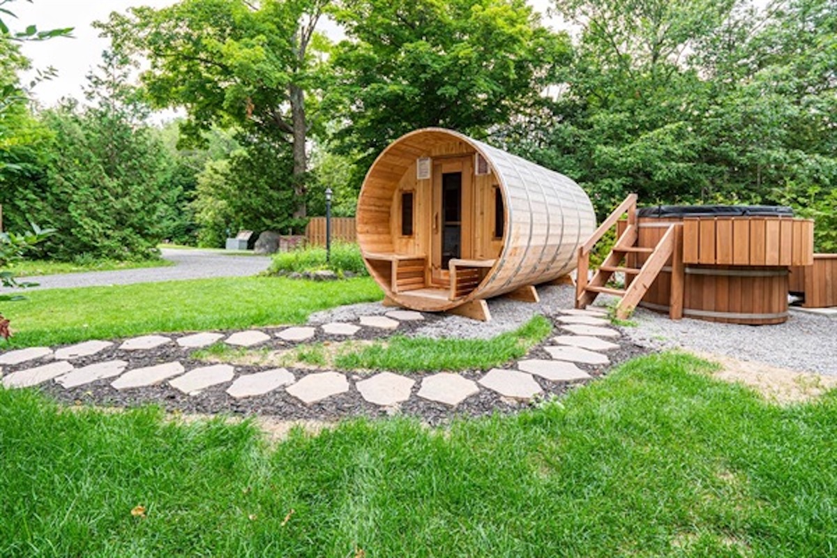 Private barrel sauna and hot tub with landscaped pathway