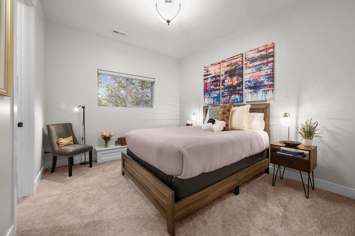 Comfortable downstairs queen bedroom featuring soft natural light, cozy furnishings, and peaceful mountain retreat vibes.