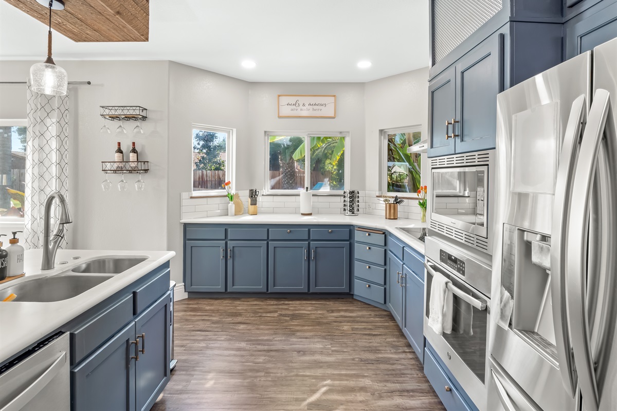 Bright chef-style kitchen with custom blue cabinetry, stainless steel appliances, sleek quartz countertops, and generous prep space—designed for effortless entertaining and elevated vacation living.
