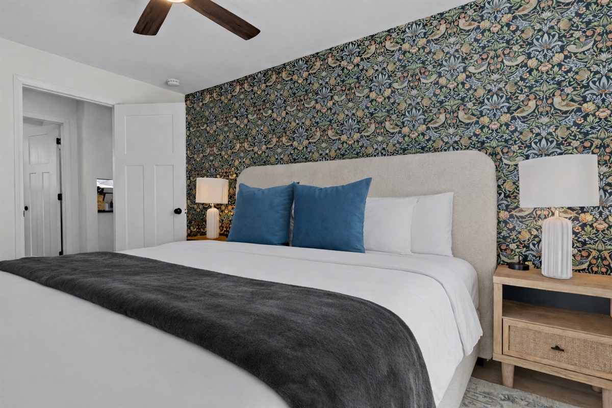 Comfortable, thoughtfully designed bedroom with a plush bed, ceiling fan, soft lighting, and a stylish accent wall for a relaxing retreat.