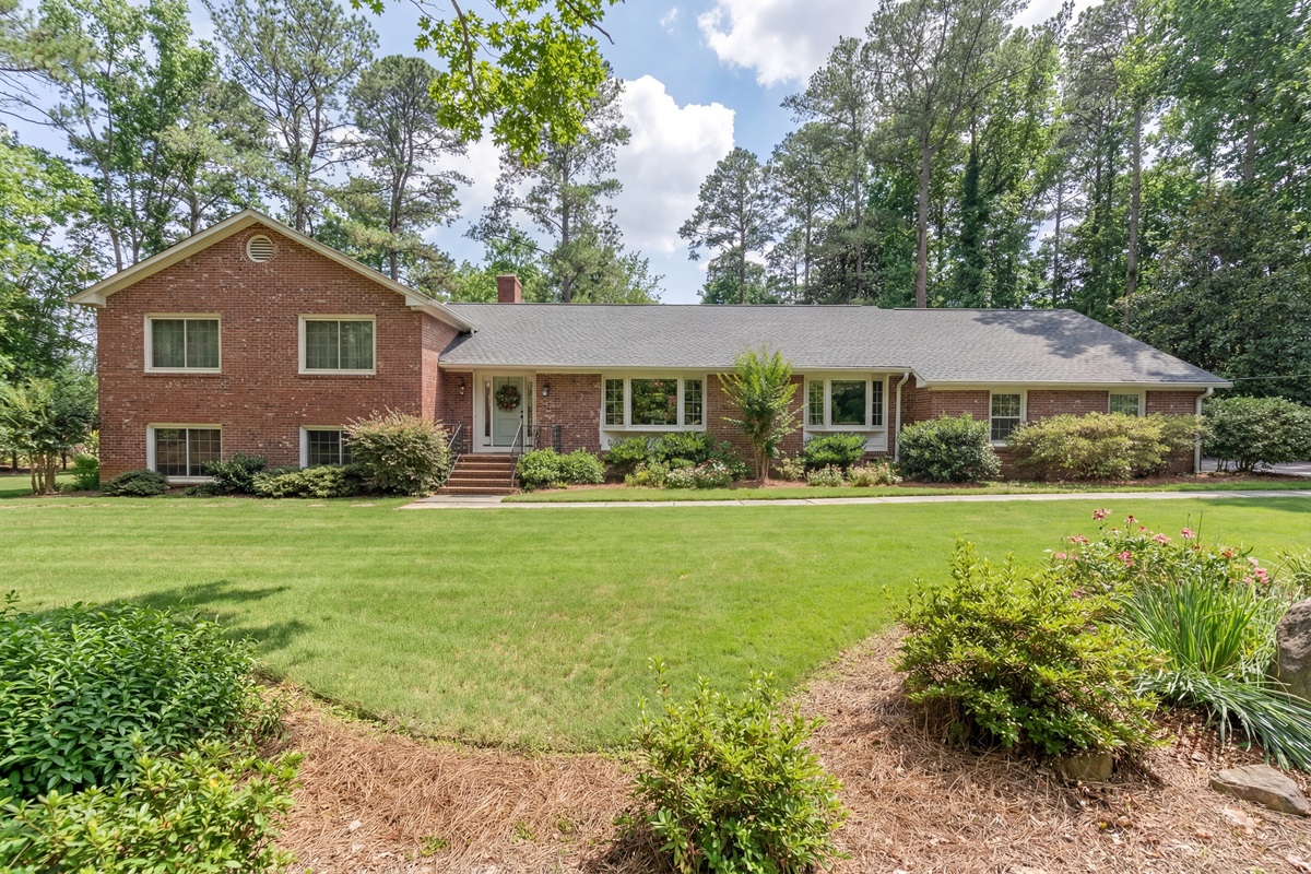 Classic brick home surrounded by trees and lush landscaping