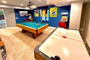 An entertainment haven featuring a pool table, two arcade machines, an air hockey table, and a Smart TV—perfect for endless fun and relaxation