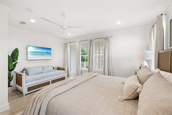 The spacious upstairs king suite offers a relaxing coastal retreat with a king bed, a daybed with a pull-out trundle provides extra sleeping space for children or additional guests.  Doors open to a private balcony furnished with two Adirondack chairs.