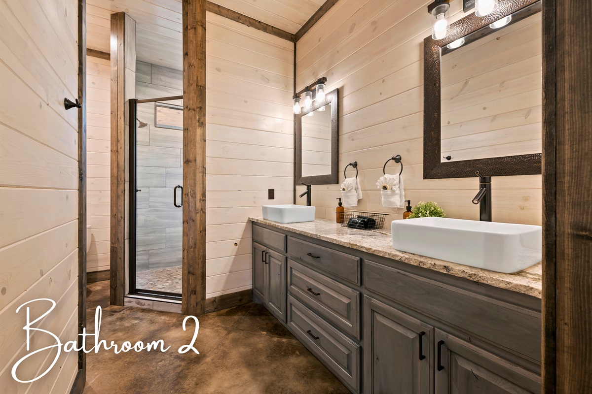 A well-designed bathroom featuring a double vanity, stylish lighting, and a glass-enclosed shower creates a harmonious blend of elegance and functionality.