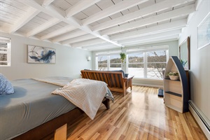 The lake bedroom, featuring a queen bed ,a long chair and and a amazing view to the lake