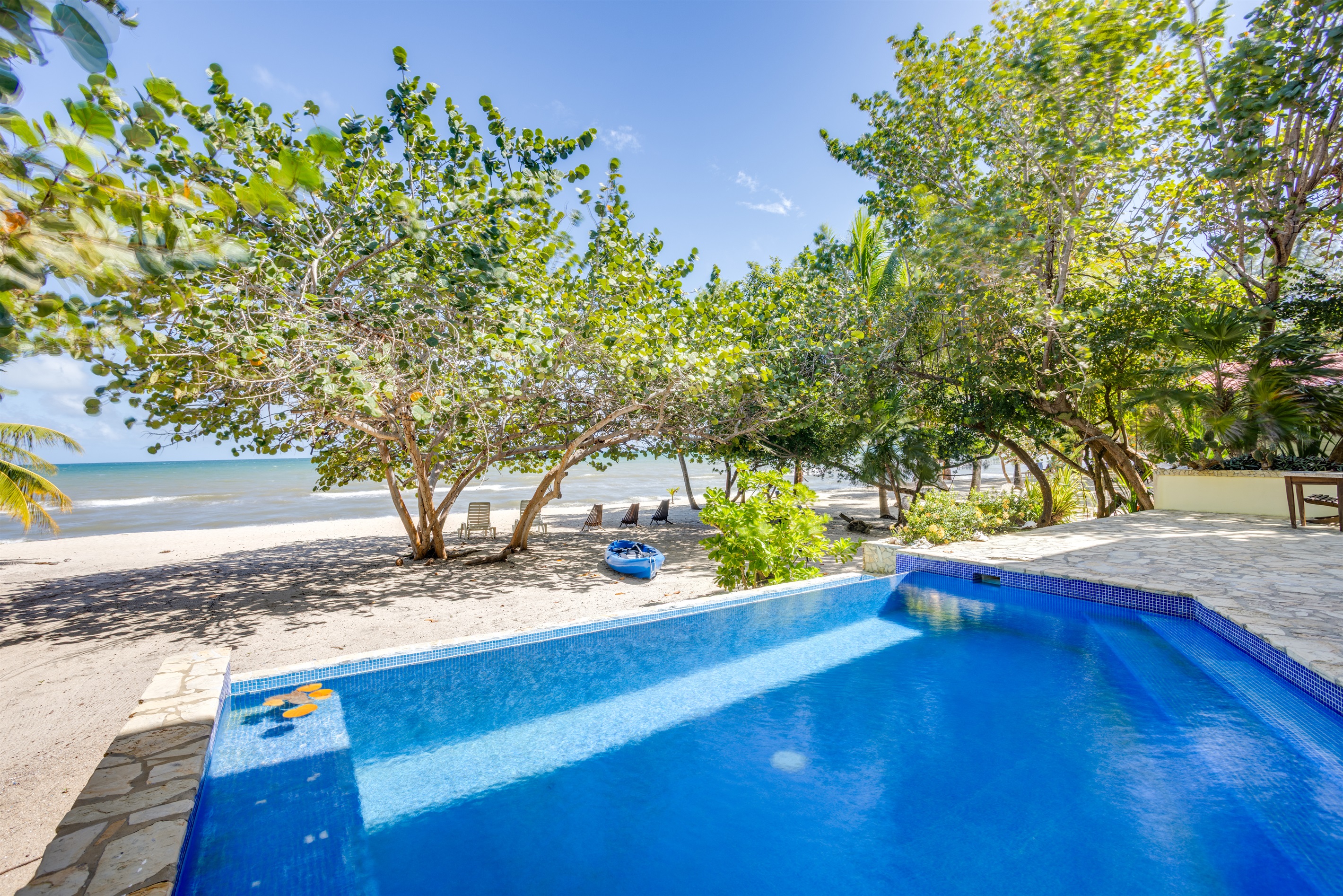 Pool on the beach with kayak, beach loungers and chairs