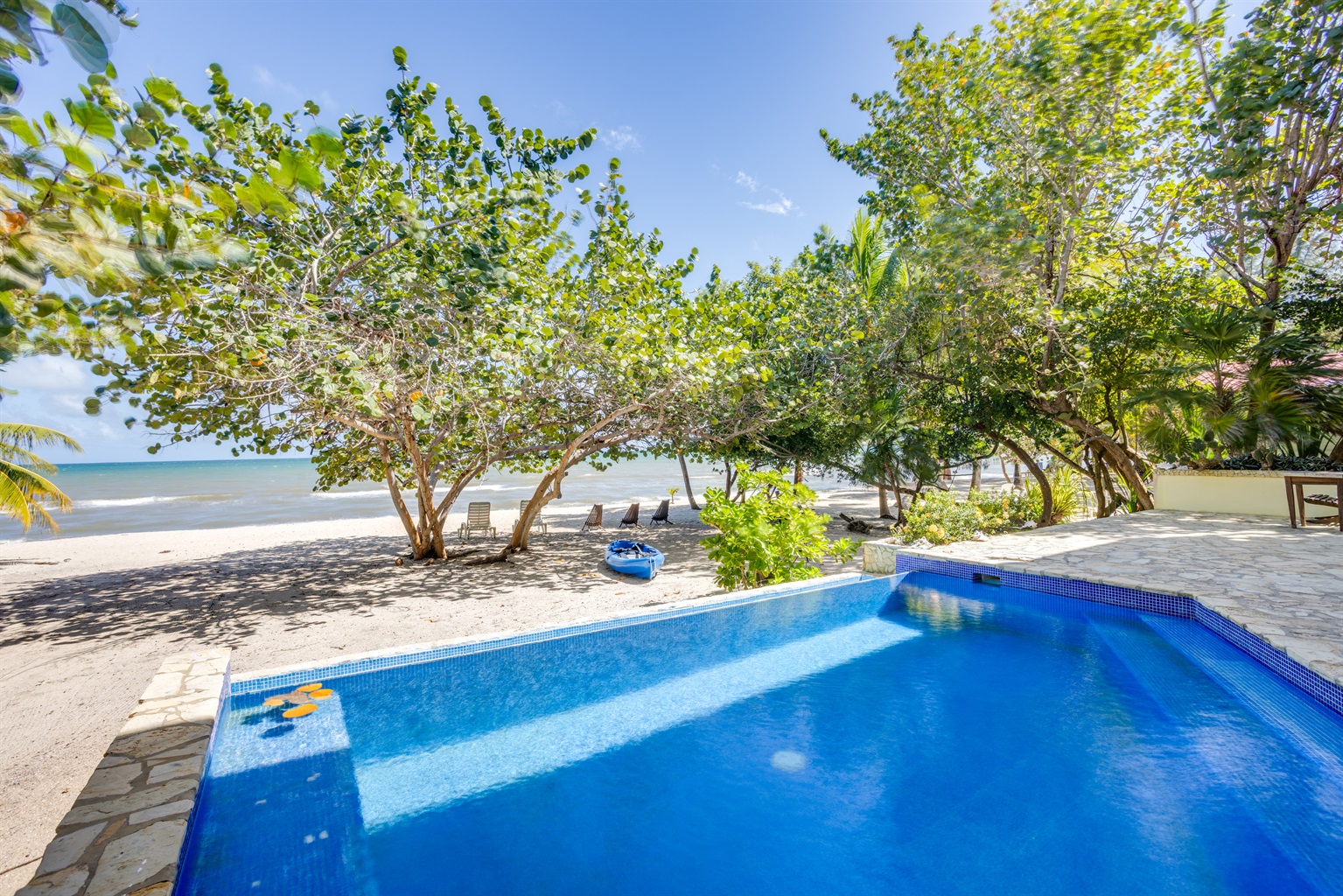 Pool on the beach with kayak, beach loungers and chairs