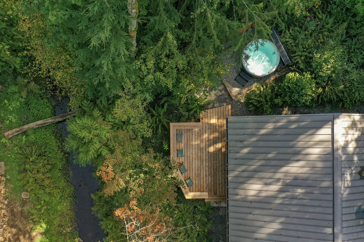 Tucked along the creek and surrounded by trees, this aerial view captures the peaceful setting of your private hot tub and deck.