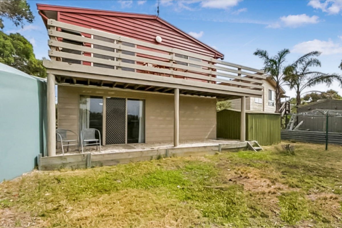 The rear yard at Carlenes Getaway includes a lower patio, upper balcony and open outdoor space for an easy Loch Sport stay.