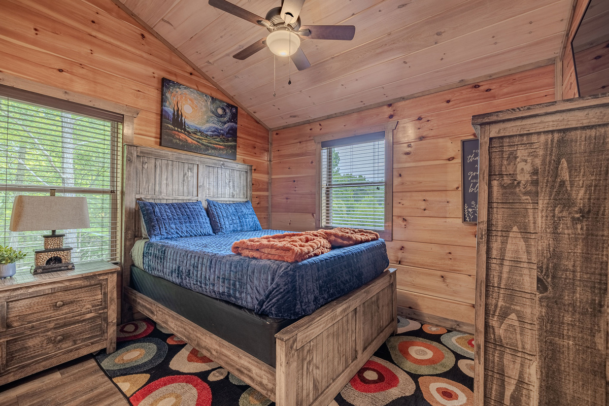 The Stargazer Suite is a cozy upper-level retreat with warm wood, layered bedding, and a calm mountain-night inspired feel.