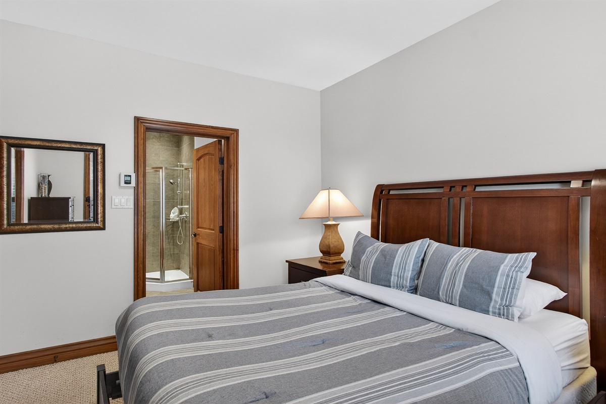 Main floor queen bedroom w/ cozy bedding & warm tones.