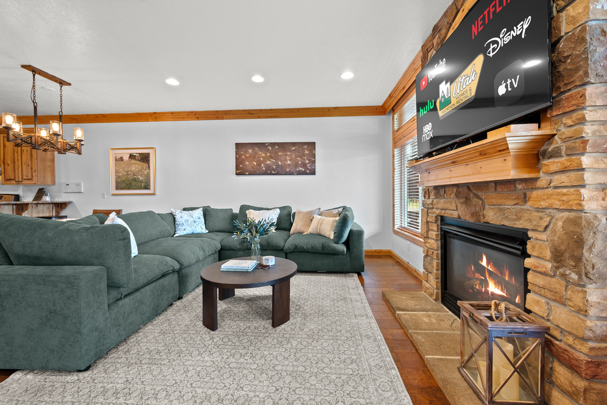 Spacious open-concept living area with comfortable seating , fireplace, large smart TV, and mountain-inspired décor.