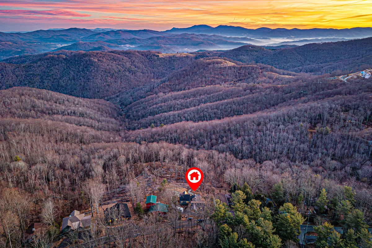 Aerial view showing the home tucked into the mountains with sweeping valley views.