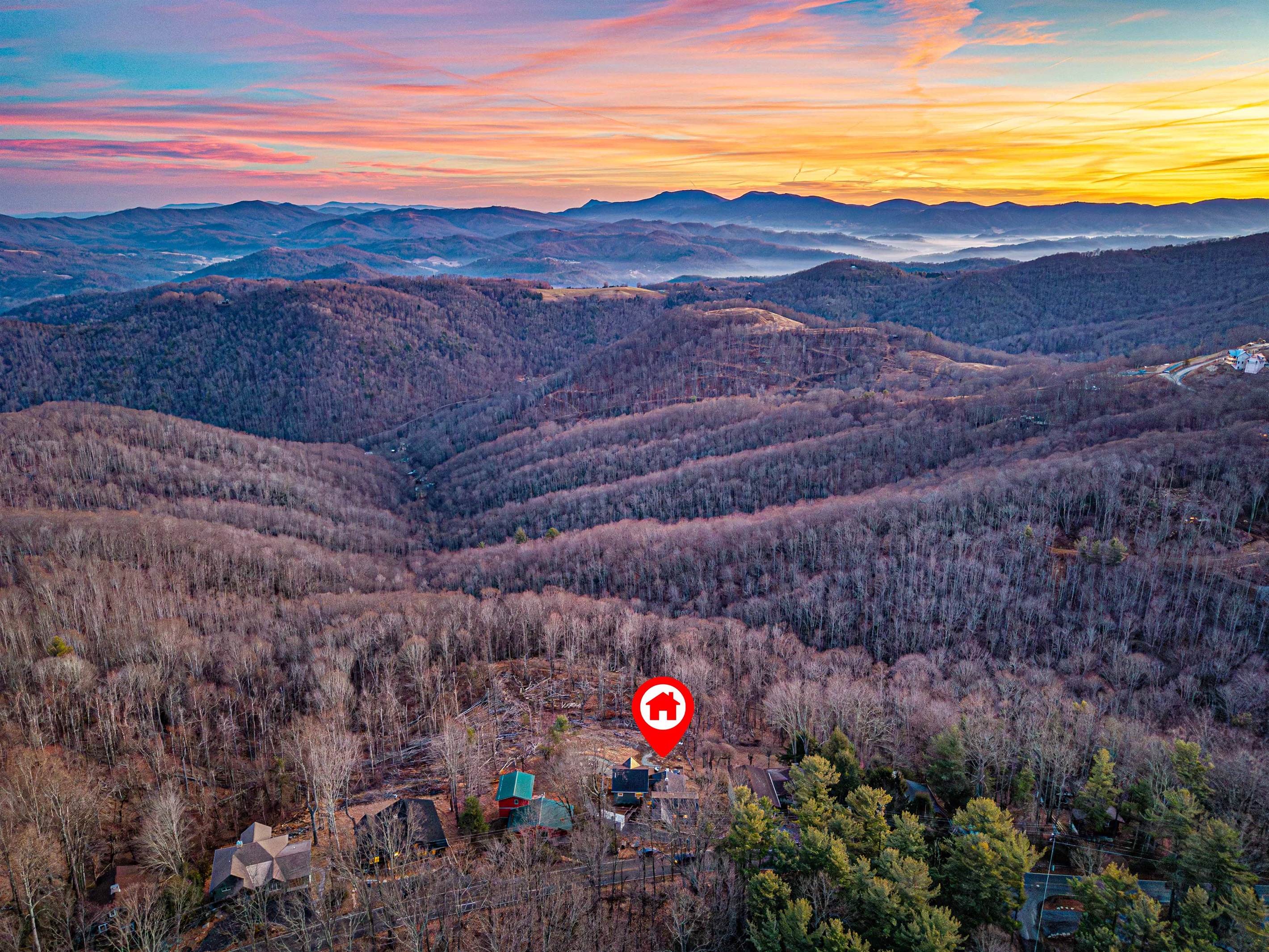 Aerial view showing the home tucked into the mountains with sweeping valley views.