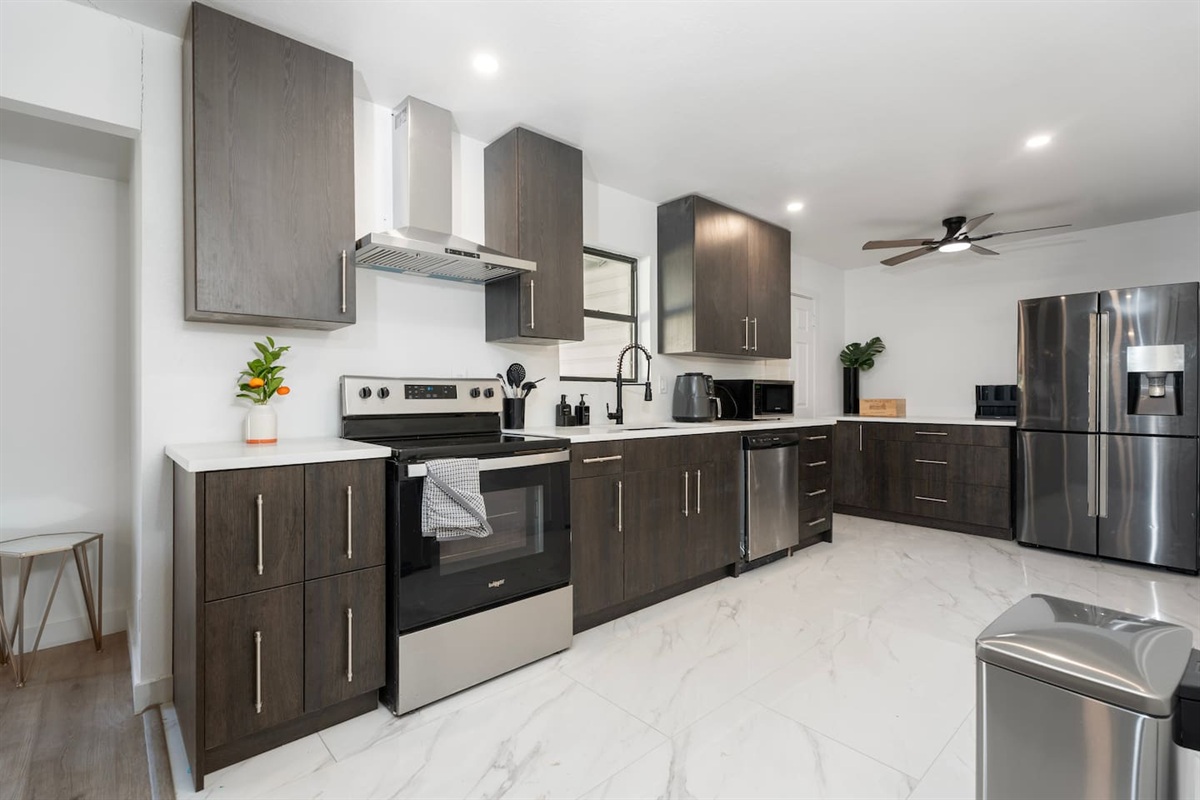 Bright and fully equipped kitchen featuring an electric stove, single oven, dishwasher, full-size fridge, Keurig coffee machine, and microwave. Complete with pots, pans, oil, salt, and pepper, this space is perfect for cooking up a storm!