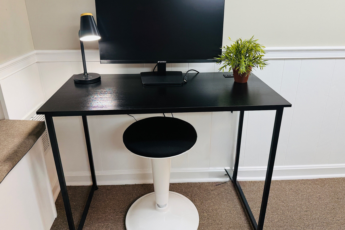 Dedicated workspace with a monitor, desk lamp, and comfortable task chair.