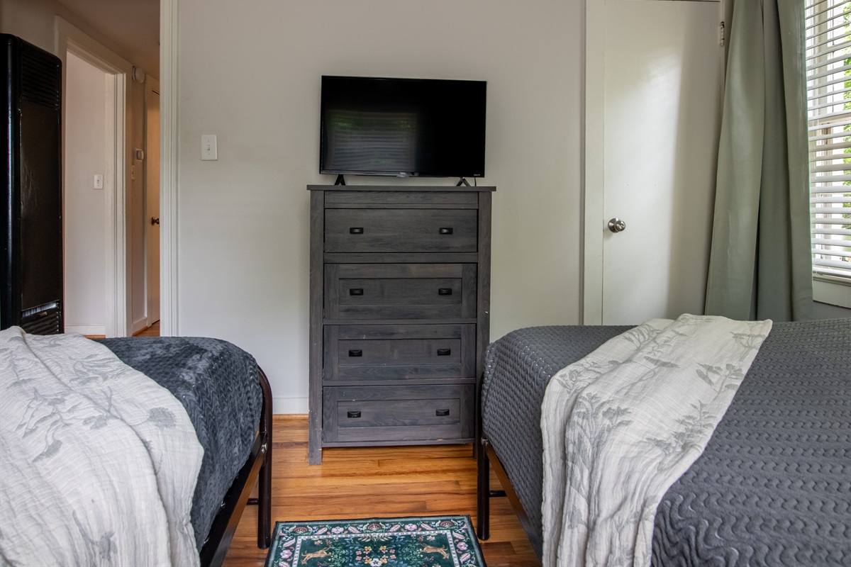 Another view of the twin room setup with dresser, TV, and plenty of space.