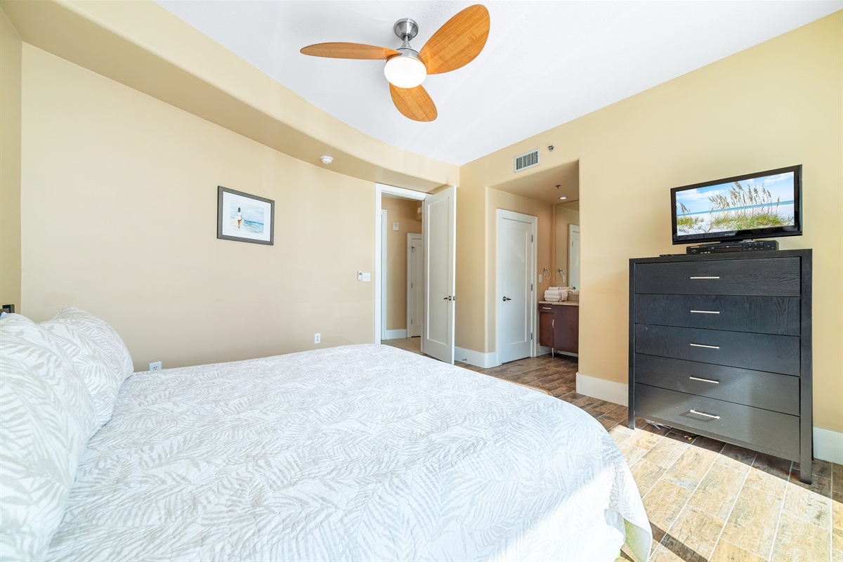 This charming guest room offers a comfortable king-size bed with crisp white linens, complemented by practical storage solutions. A delightful space to unwind.