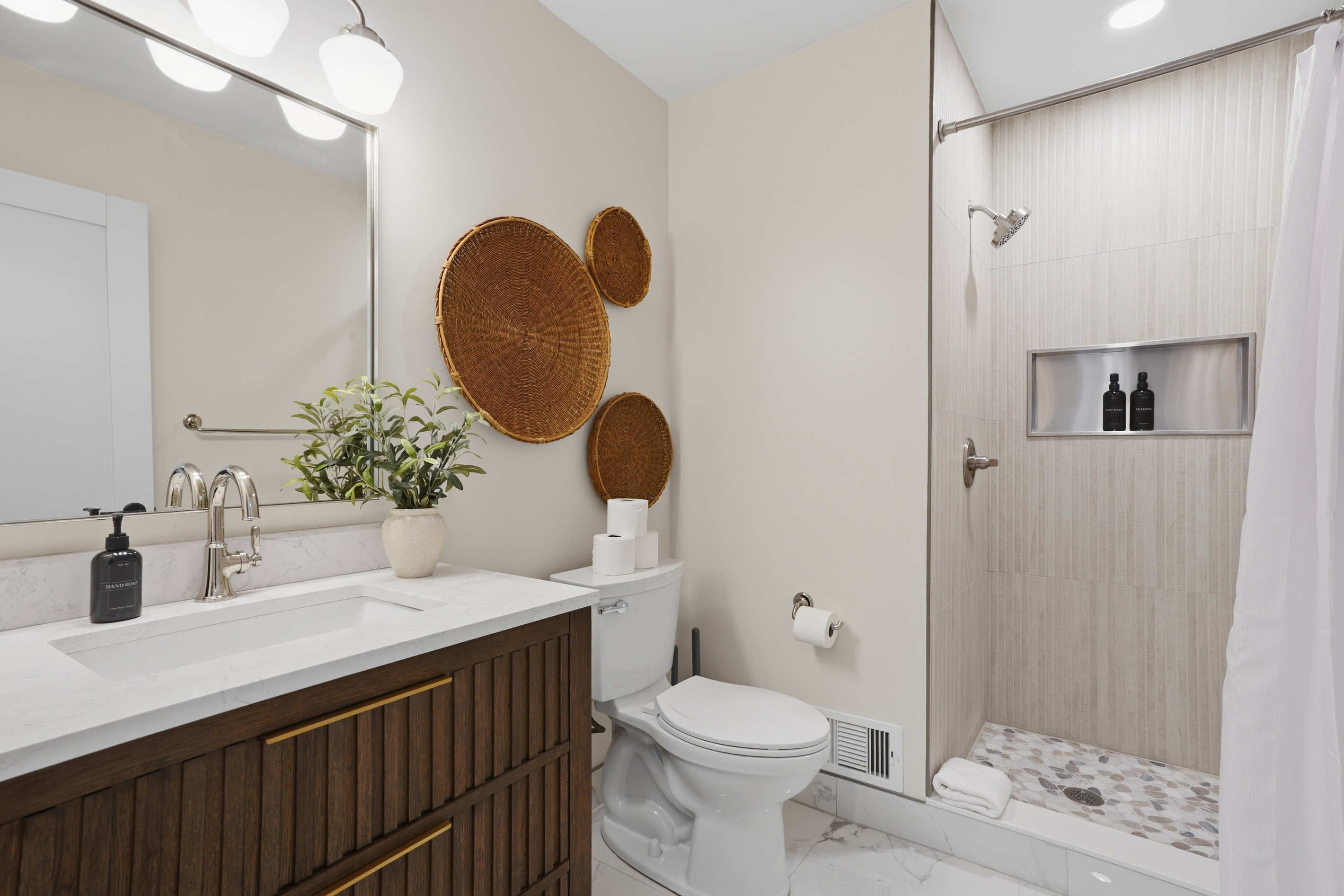 Modern, spa-inspired bathroom with a clean double vanity, quartz countertop, and warm wood accents. Features a sleek walk-in shower with built-in niche and soft neutral finishes, creating a bright, calm, and upscale hotel-like experience.