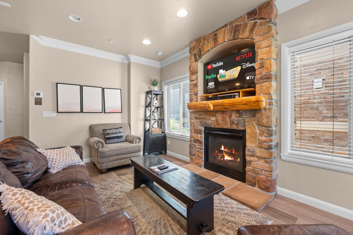Inviting living room featuring plush leather seating, a stone fireplace, and Smart TV for movie nights.