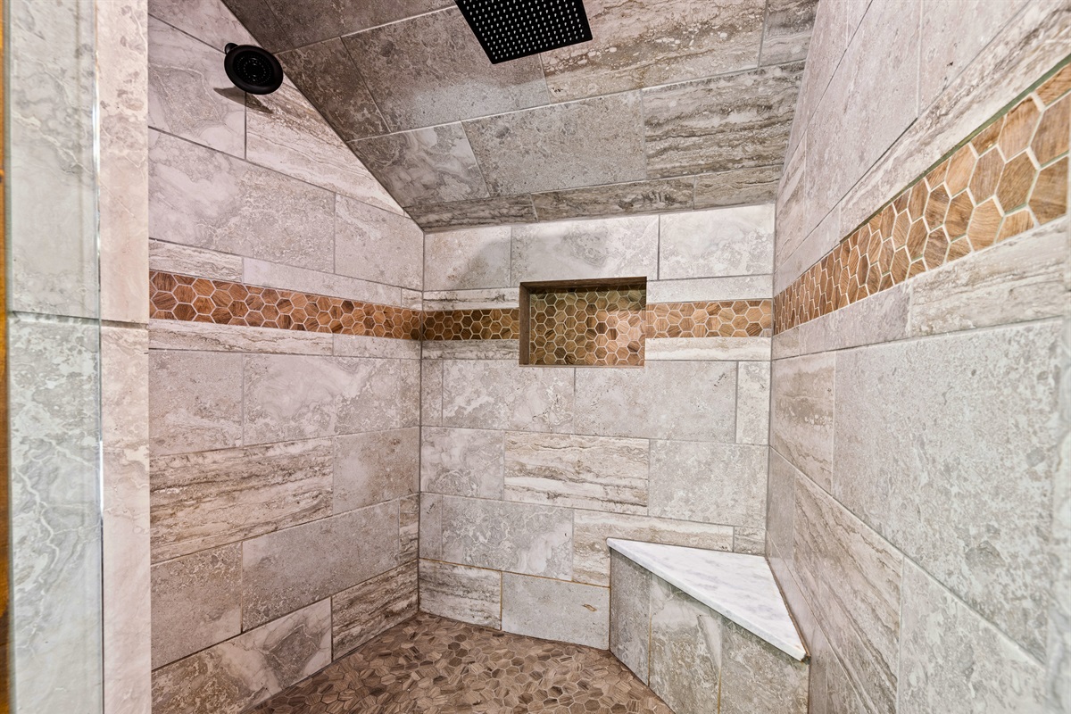 The walk-in shower showcases detailed tile work and a clean, modern design, offering a refreshing and spa-like experience.