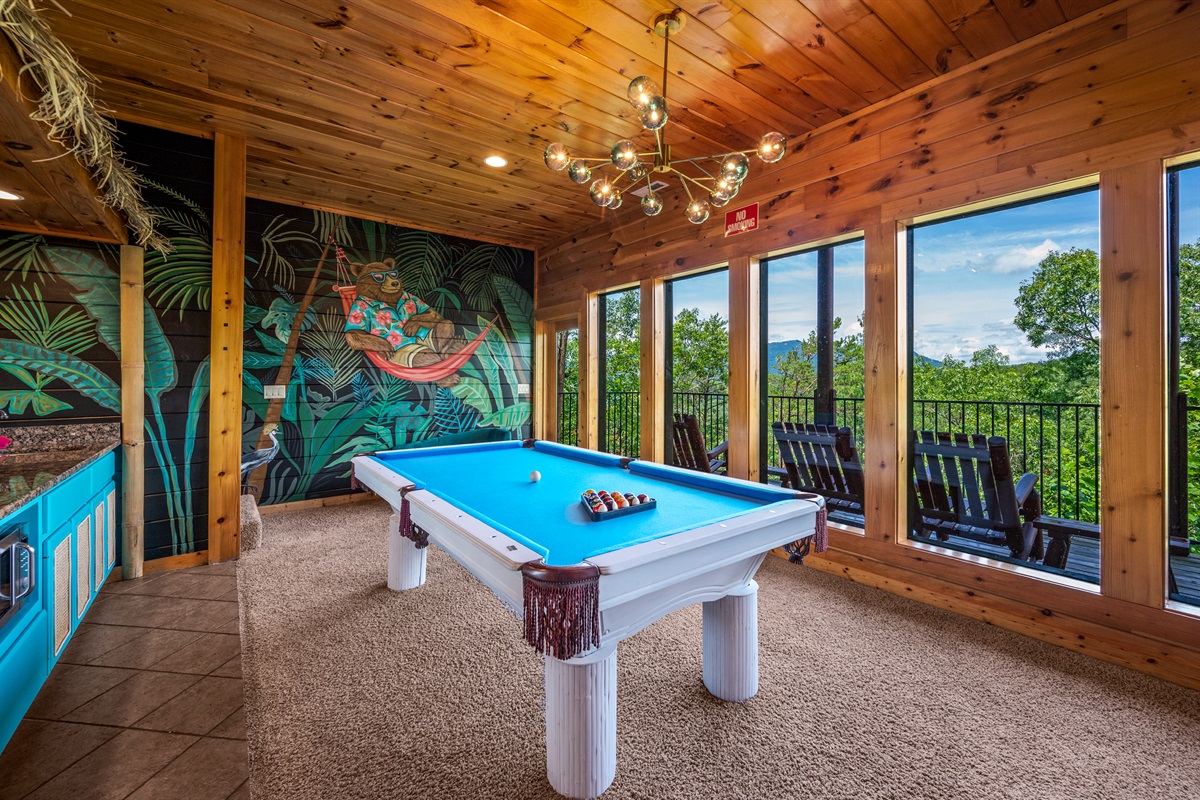 Game room with large windows offering a scenic mountain views and access to a balcony with rocking chairs