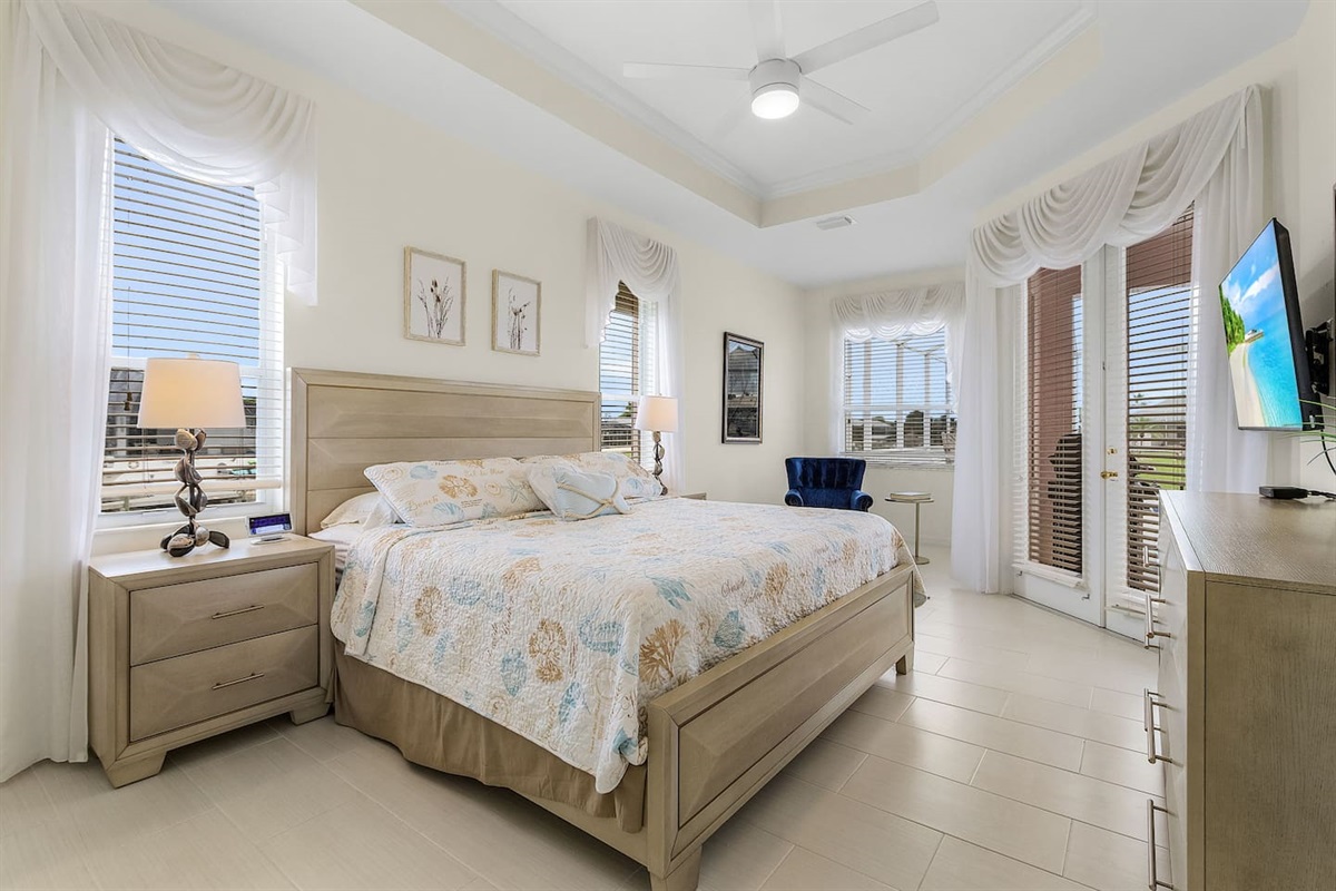 Beautiful coastal-designed primary bedroom with a king-size bed, TV, and direct access to the pool and lanai area!