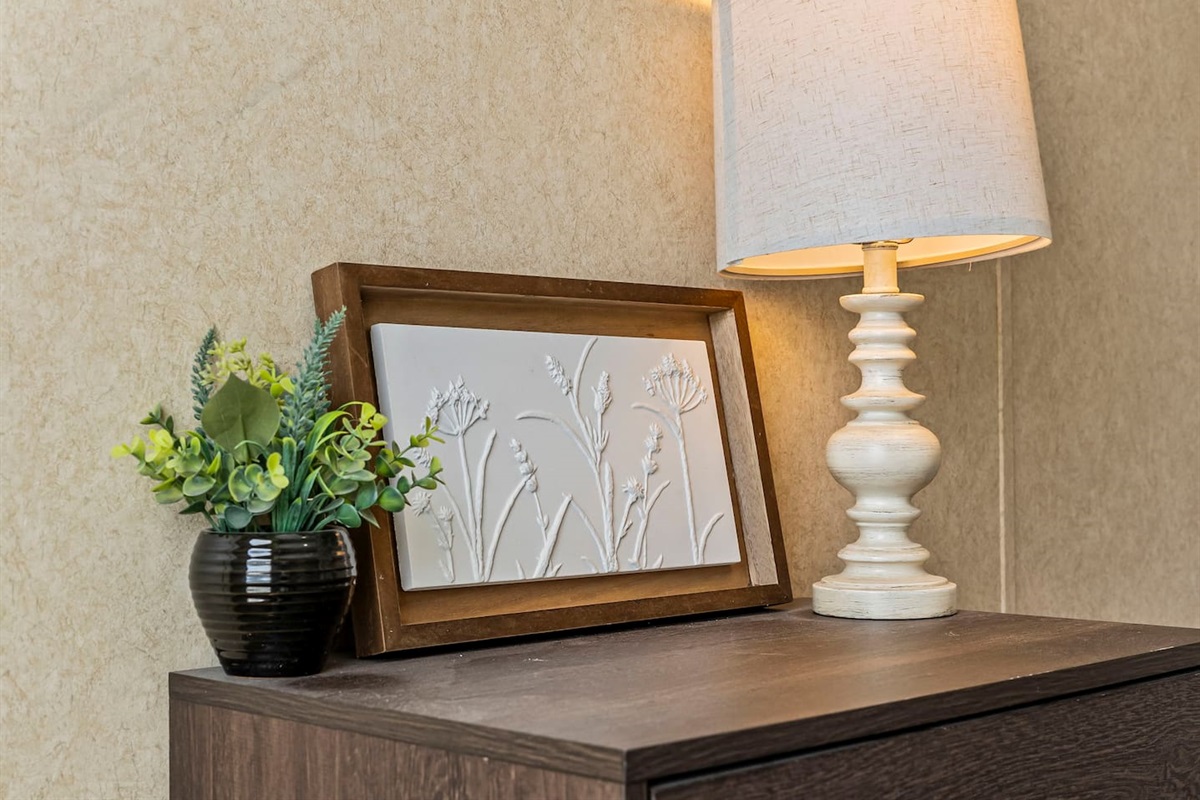 Charming bedside setup with a lamp, greenery, and elegant décor for a cozy, home-like feel.