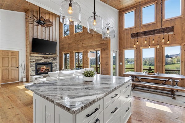Gourmet kitchen with a massive stone island, white shaker cabinets, and stunning floor-to-ceiling windows overlooking the pasture and mountains. Fully equipped for baking with all the tools you need to cook and entertain with ease.