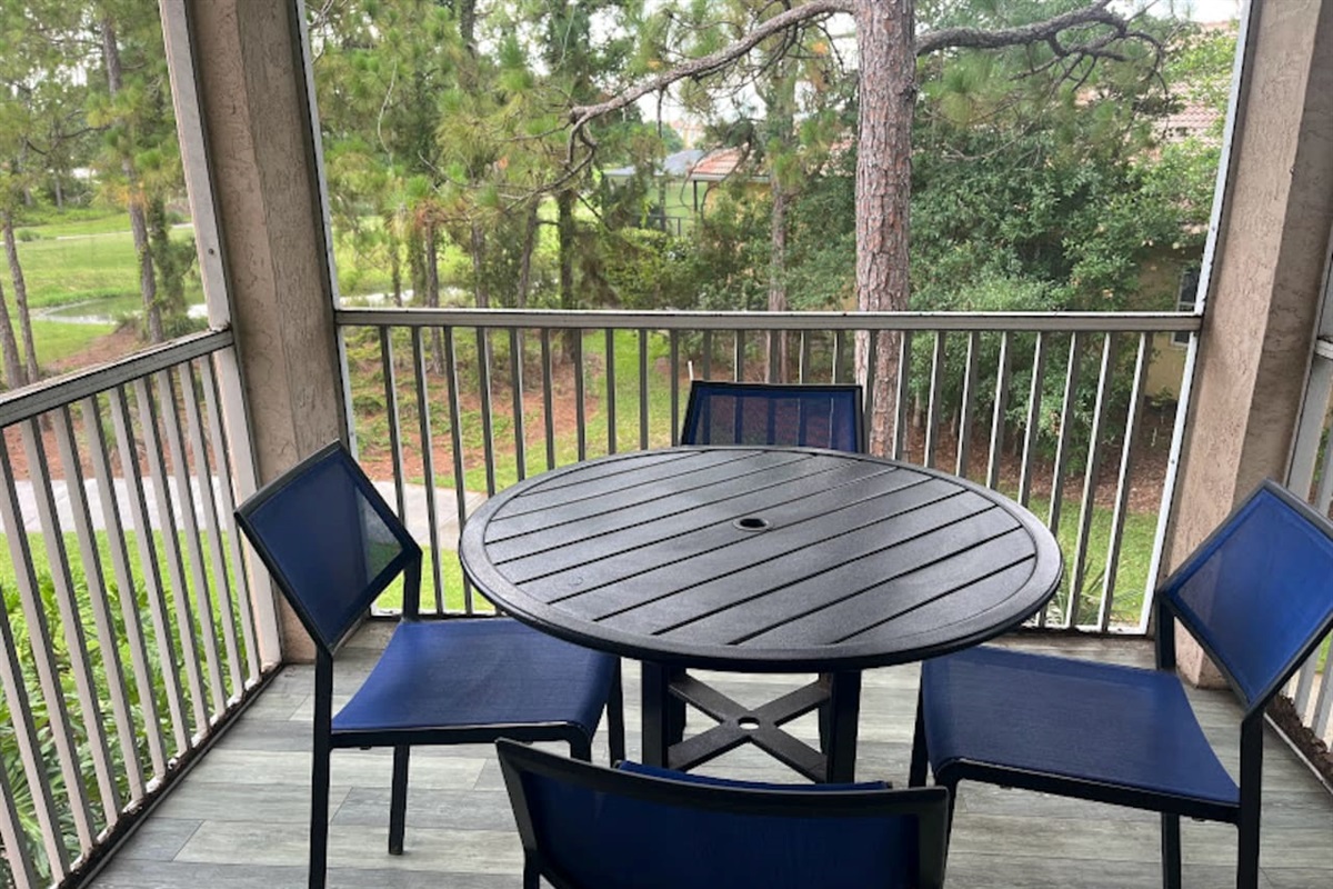 Private screened balcony with outdoor seating and peaceful views of the surrounding greenery.