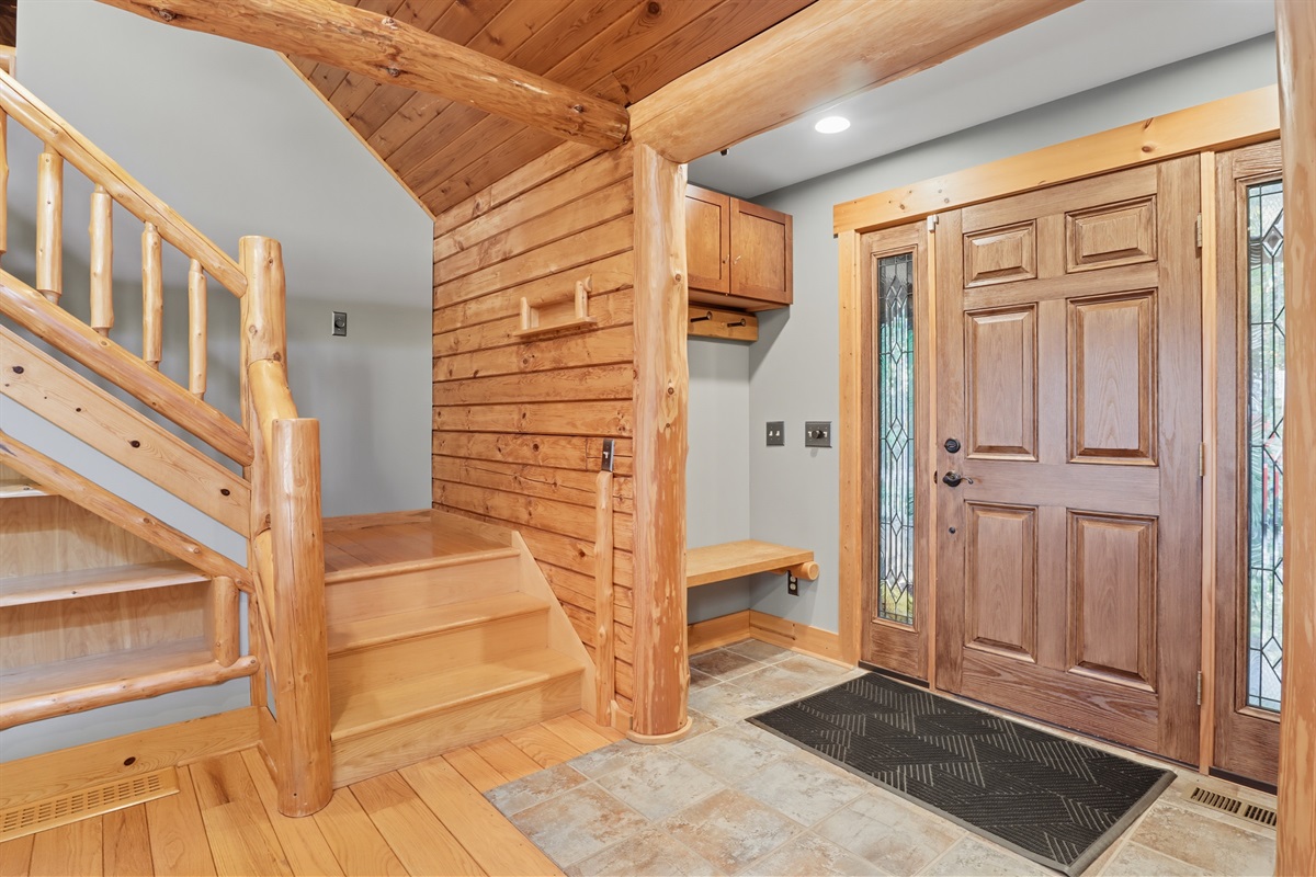 Warm wood entryway with rustic staircase welcoming you inside.
