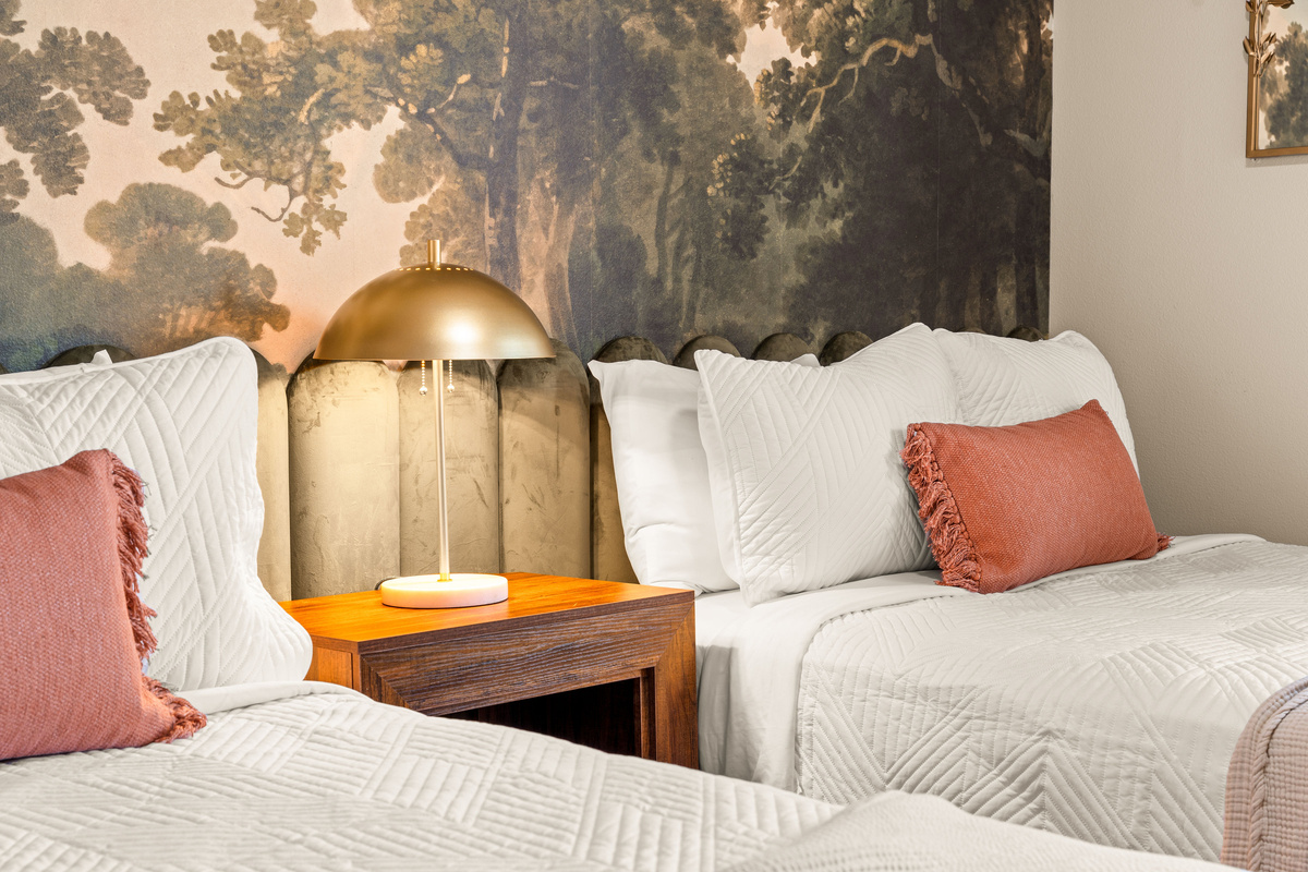 Woodland Bedroom Details
    Soft linens, warm coral accents, and golden bedside lighting complement the dramatic woodland mural, creating a cozy retreat inspired by the beauty of the Ozarks.