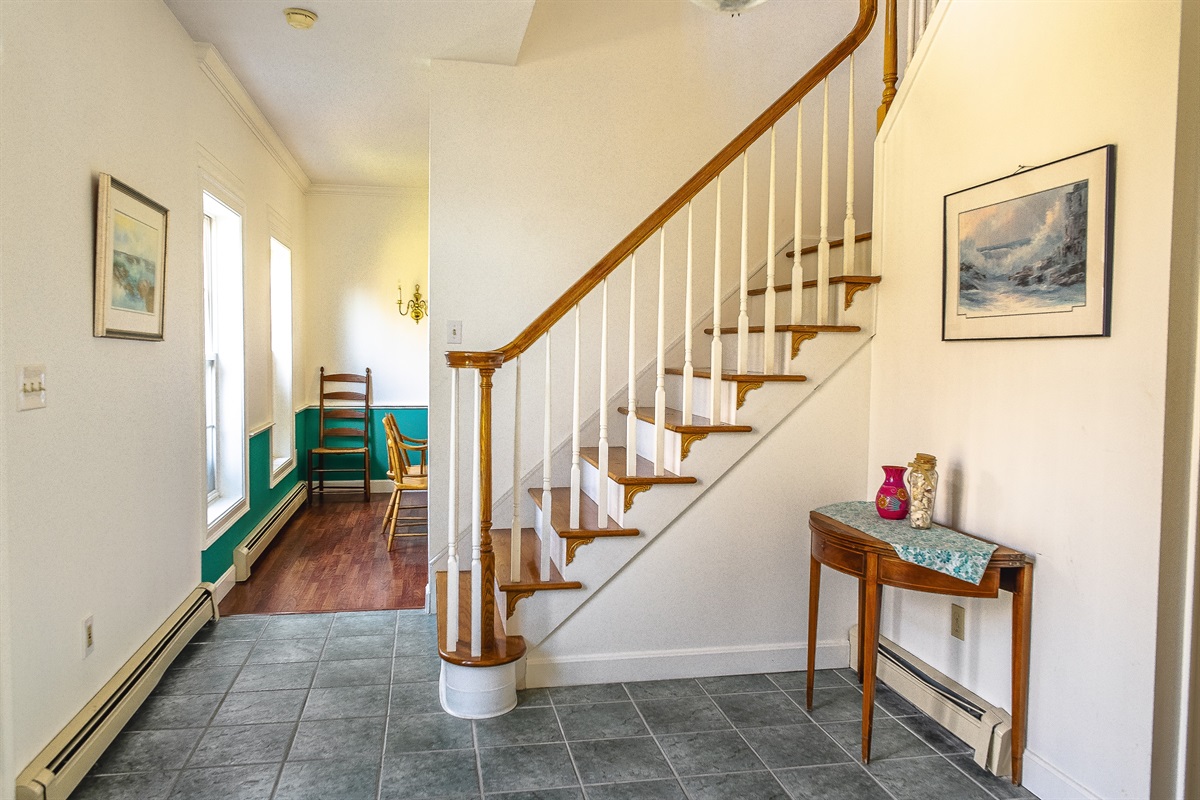 The grand foyer flows seamlessly into the formal dining room, perfect for hosting a Maine lobster dinner. This open layout allows your group to move easily between the entryway and gathering spaces after a day exploring Acadia National Park.