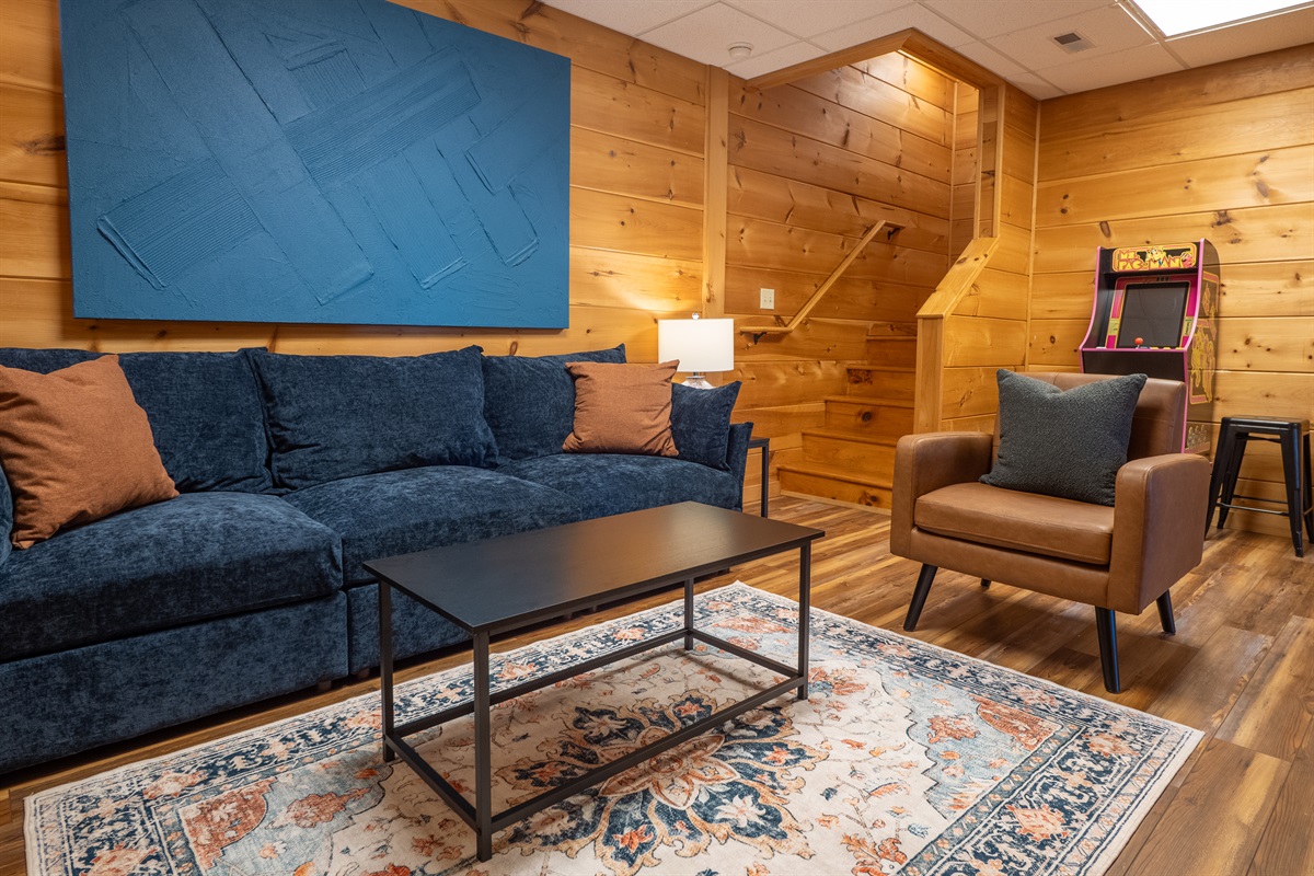 The lower level is where the fun begins! The cozy living area is your hub for fun and relaxation, complete with comfy seating and an arcade game!