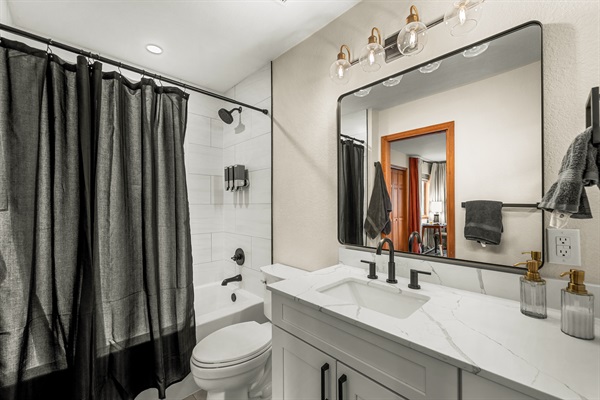 🚿✨ Full ensuite bathroom in the main-level primary (master) bedroom: fresh and modern with a sleek vanity, bright mirror lighting, and a clean tub/shower combo—stocked with essentials for an easy, comfortable stay.